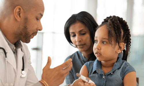 Doctor explaining an insulin delivery pen to female child patient and her mother