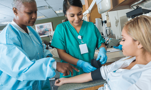 Two female health care professionals preparing to administer a blood test on a female patient