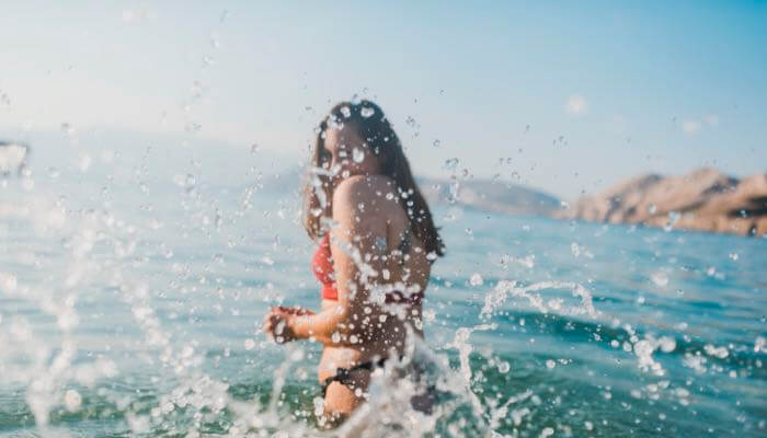 Woman wading in ocean wearing water-resistant blood glucose monitoring smartwatch