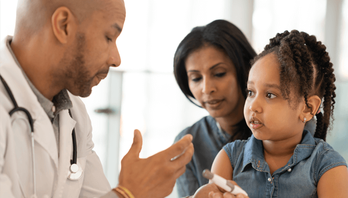 Diverse male health professional showing minor female patient with parent how to use an insulin pen